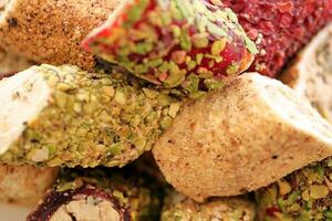 Rolls of turkish delight with many different flavors and fillings close up on table of vendors market photo