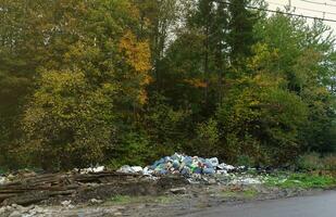 Garbage pile without dumpster scattered all over the street in forest photo