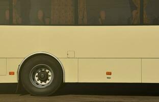 Photo of the hull of a large and long yellow bus with free space for advertising. Close-up side view of a passenger vehicle for transportation and tourism