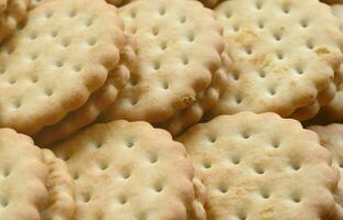 Detailed picture of round sandwich cookies with coconut filling. Background image of a close-up of several treats for tea photo