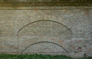 Very old brick stone wall of castle or fortress of 18th century. Full frame wall with obsolete dirty and cracked bricks photo