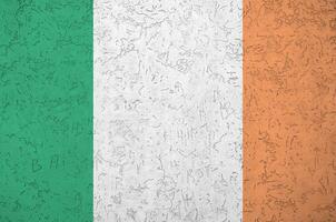 Ireland flag depicted in bright paint colors on old relief plastering wall. Textured banner on rough background photo