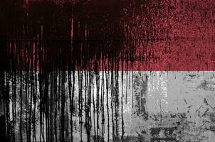 Monaco flag depicted in paint colors on old and dirty oil barrel wall closeup. Textured banner on rough background photo