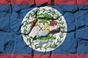 Belize flag depicted in paint colors on old stone wall closeup. Textured banner on rock wall background photo