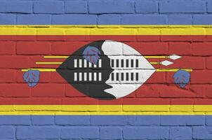 Swaziland flag depicted in paint colors on old brick wall. Textured banner on big brick wall masonry background photo