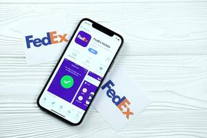 kharkov, ucrania - 5 de marzo de 2021 icono de fedex y aplicación de la tienda de aplicaciones en la pantalla de visualización del iphone 12 pro en la mesa blanca foto