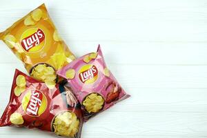 KHARKOV, UKRAINE - JANUARY 3, 2021 Various flavoured of lay's potato chips on wooden background. Lay's has been owned by PepsiCo through Frito-Lay in 1965 photo