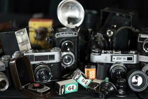 KHARKOV, UKRAINE - APRIL 27, 2021 Film photo cameras and another old retro photo equipment on black wooden table in photographer darkroom. Photographic gear from soviet union