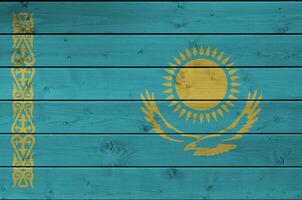 Kazakhstan flag depicted in bright paint colors on old wooden wall. Textured banner on rough background photo