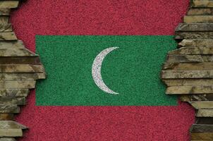 Maldives flag depicted in paint colors on old stone wall closeup. Textured banner on rock wall background photo