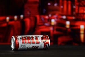 KHARKOV, UKRAINE - FEBRUARY 14, 2021 Hell energy drink can on black wooden table with red interior background photo