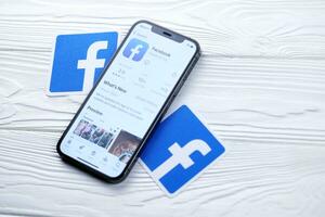 KHARKOV, UKRAINE - MARCH 5, 2021 Facebook icon and application from App store on iPhone 12 pro display screen on white table photo