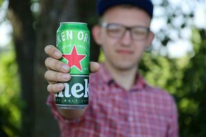 KHARKOV, UKRAINE - JULY 31, 2021 Man with green tin can of Heineken lager beer produced by the Dutch brewing company Heineken N.V. photo