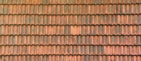 Close up of red terracotta roof shingles with some mildew. Background texture of roofing material photo