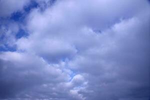 Beautiful cloud formations in the sky with sunlight behind. White clouds on dramatic blue sky photo