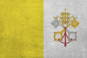 Vatican City State flag depicted in bright paint colors on old relief plastering wall. Textured banner on rough background photo