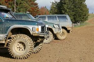 Automobile in a countryside landscape with a mud road. Off-road 4x4 suv automobile with ditry body after drive in muddy road photo