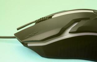 Closeup of a black gaming optical mouse on a blue background photo