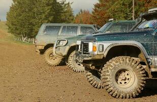 Automobile in a countryside landscape with a mud road. Off-road 4x4 suv automobile with ditry body after drive in muddy road photo