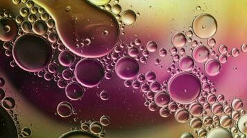 huile alimentaire colorée abstraite laisse tomber des bulles et des sphères qui coule sur la surface de l'eau video