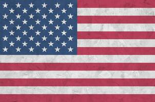 United States of America flag depicted in bright paint colors on old relief plastering wall. Textured banner on rough background photo