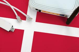 Denmark flag depicted on table with internet rj45 cable, wireless usb wifi adapter and router. Internet connection concept photo