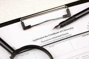 N-600 Application for Certificate of Citizenship blank form on A4 tablet lies on office table with pen and magnifying glass photo