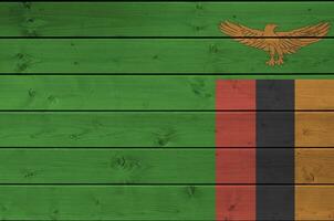 Zambia bandera representado en brillante pintar colores en antiguo de madera pared. texturizado bandera en áspero antecedentes foto