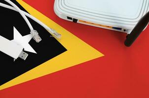 Timor Leste flag depicted on table with internet rj45 cable, wireless usb wifi adapter and router. Internet connection concept photo