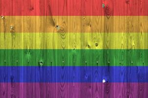 LGBT community flag depicted in bright paint colors on old wooden wall. Textured banner on rough background photo