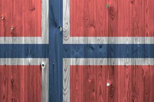 Noruega bandera representado en brillante pintar colores en antiguo de madera pared. texturizado bandera en áspero antecedentes foto