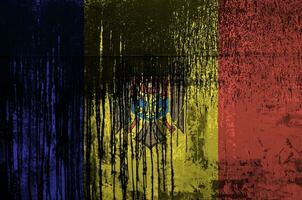 Moldova flag depicted in paint colors on old and dirty oil barrel wall closeup. Textured banner on rough background photo