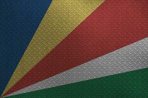 Seychelles flag depicted in paint colors on old brushed metal plate or wall closeup. Textured banner on rough background photo