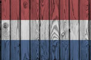 Netherlands flag depicted in bright paint colors on old wooden wall. Textured banner on rough background photo