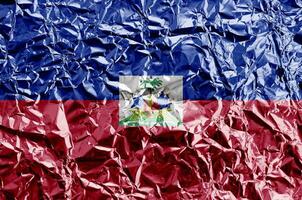 Haiti flag depicted in paint colors on shiny crumpled aluminium foil closeup. Textured banner on rough background photo