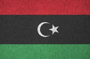 Libya flag depicted in bright paint colors on old relief plastering wall. Textured banner on rough background photo