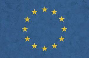 European union flag depicted in bright paint colors on old relief plastering wall. Textured banner on rough background photo