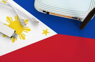 Philippines flag depicted on table with internet rj45 cable, wireless usb wifi adapter and router. Internet connection concept photo