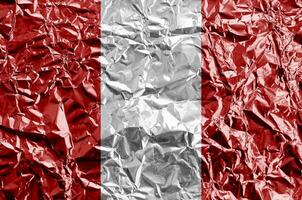 Peru flag depicted in paint colors on shiny crumpled aluminium foil closeup. Textured banner on rough background photo