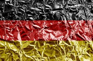 Germany flag depicted in paint colors on shiny crumpled aluminium foil closeup. Textured banner on rough background photo