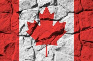 Canadá bandera representado en pintar colores en antiguo Roca pared de cerca. texturizado bandera en rock pared antecedentes foto