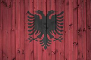 Albania bandera representado en brillante pintar colores en antiguo de madera pared. texturizado bandera en áspero antecedentes foto