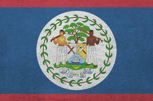 Belize flag depicted in bright paint colors on old relief plastering wall. Textured banner on rough background photo