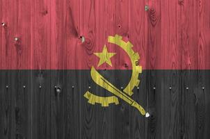 angola bandera representado en brillante pintar colores en antiguo de madera pared. texturizado bandera en áspero antecedentes foto