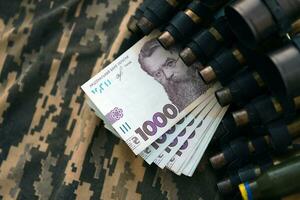 Ukrainian army machine gun belt shells and bunch of hryvnia bills on military uniform. Payments to soldiers of the Ukrainian army, salaries to the military photo