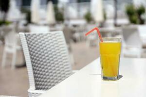 vaso de naranja jugo con el plastico Paja en blanco mesa en restaurante al aire libre salón zona foto