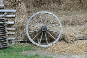 Place with stacks of hay cubes and rustic wooden wheels of old cart photo