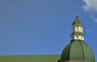 Completed perfect high-quality roofing work from metal roofing. The dome of a polyhedral shape with a spire is covered with green metal tiles photo