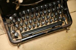 Details of an old retro typewriter in vintage style with dusty surfaces on wooden table photo