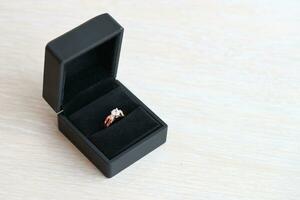 Gold diamond engagement ring in black box case on white background photo